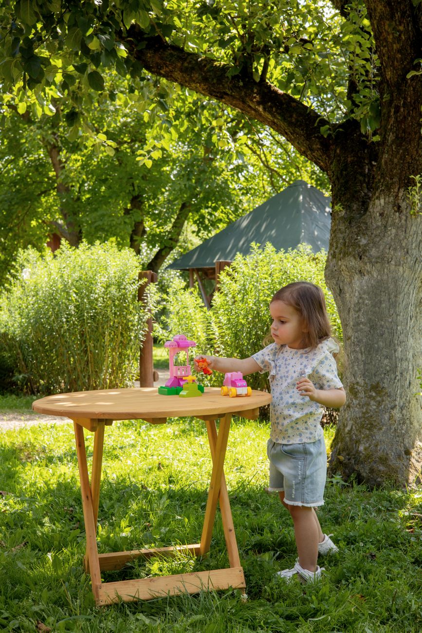 child playing with toys under a tree in summer garden